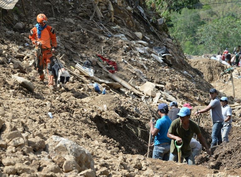 A rescuer guides his sniffer dog at the scene of the landslide in Itogon