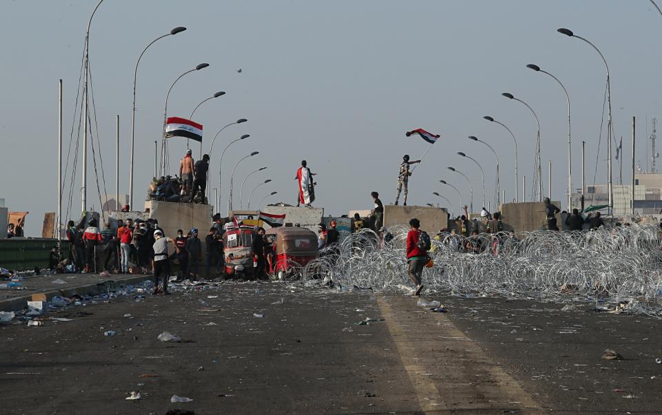 Iraqi anti-government protesters take control of concrete walls and barriers set by security forces that closes the Al-Sanak Bridge leading to the Green Zone, during a demonstration in Baghdad, Iraq, Thursday, Oct. 31, 2019. Late Wednesday, hundreds of people headed to the Al-Sanak Bridge that runs parallel to the Joumhouriya Bridge, opening a new front in their attempts to cross the Tigris River to the Green Zone. Security forces fired volleys of tear gas that billowed smoke and covered the night sky. (AP Photo/Hadi Mizban)