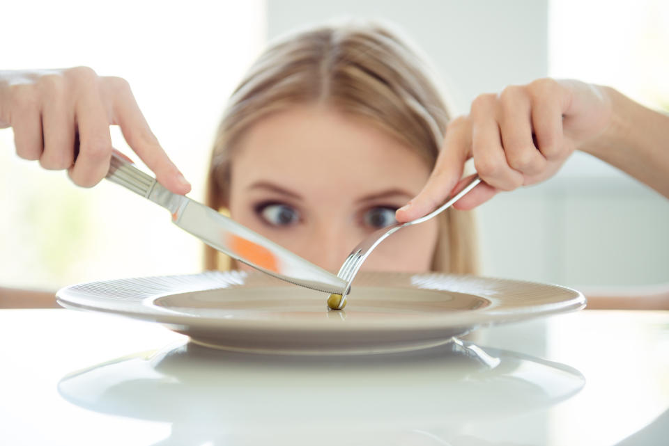 I'll eat you tiny pea! Weight loss concept. Close up photo portrait of mad lady's eye looking at small one pea on large big plate on table