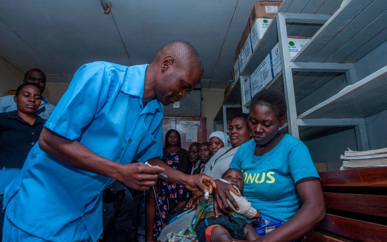 A health worker poised to give the first ever dose of a malaria vaccine outside a clinical trial - AFP