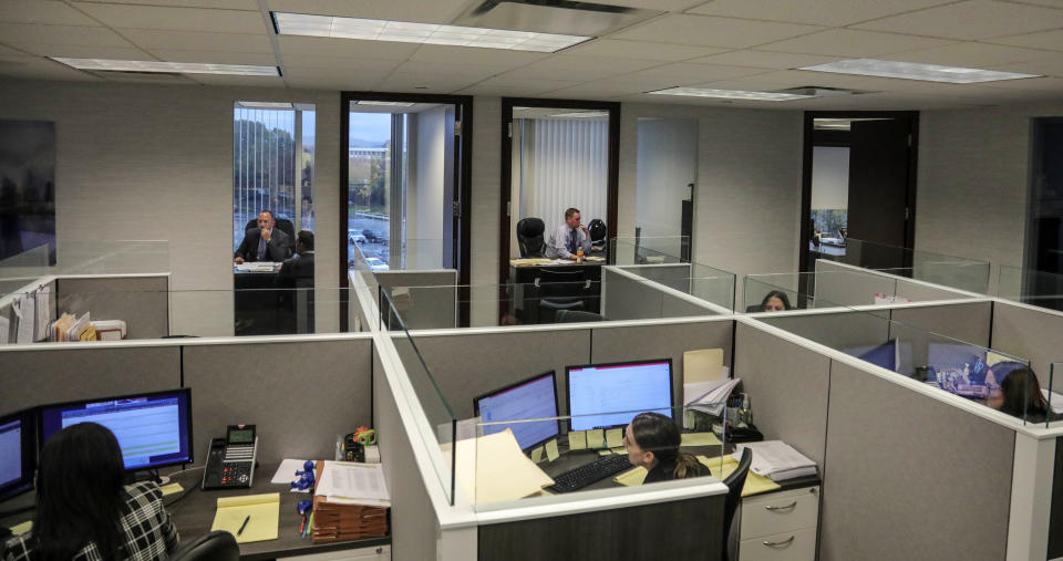 This Tuesday, Oct. 29, 2019, photo taken at the law firm of Slater, Slater and Schulman, shows lawyers Linc Leder, top left, and Michael Werner, top right, in their offices, while paralegals work in their cubicles, in Melville, N.Y. Attorney Adam Slater said since New York state opened its one-year window allowing sex abuse suits with no statute of limitations, his firm has signed up nearly 300 new clients and hired a half-dozen new paralegals to field calls. (AP Photo/Bebeto Matthews)