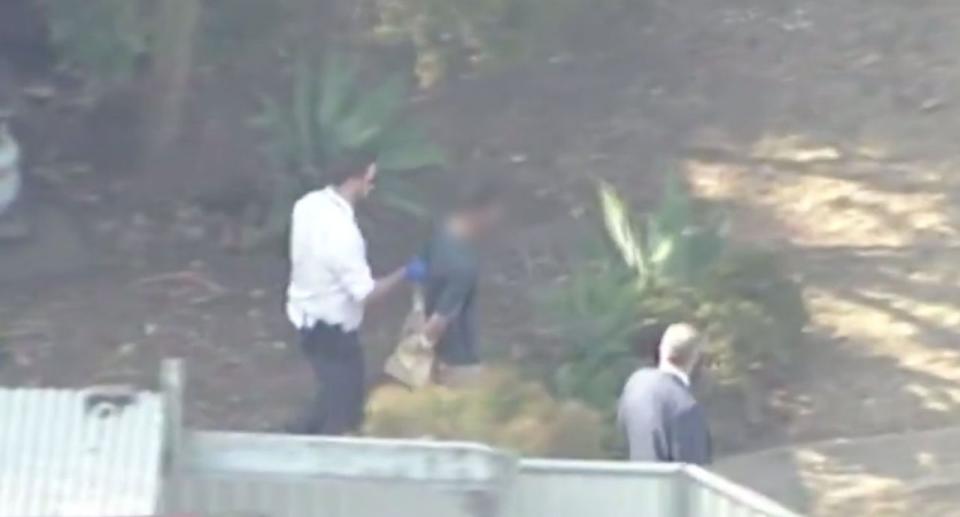 A man has been charged with two counts of murder for the double stabbing in Sydney's southwest. Pictured is a man being led away by police.