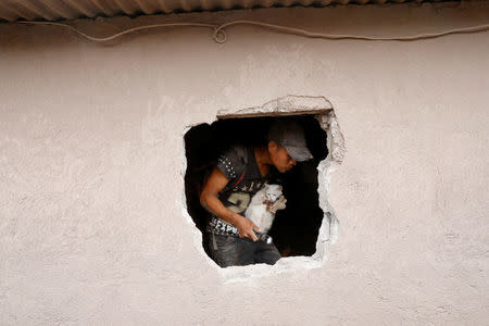 A man holds a cat as he inspects an affected area after the eruption of the Fuego volcano in Escuintla, Guatemala, June 8, 2018. REUTERS/Carlos Jasso