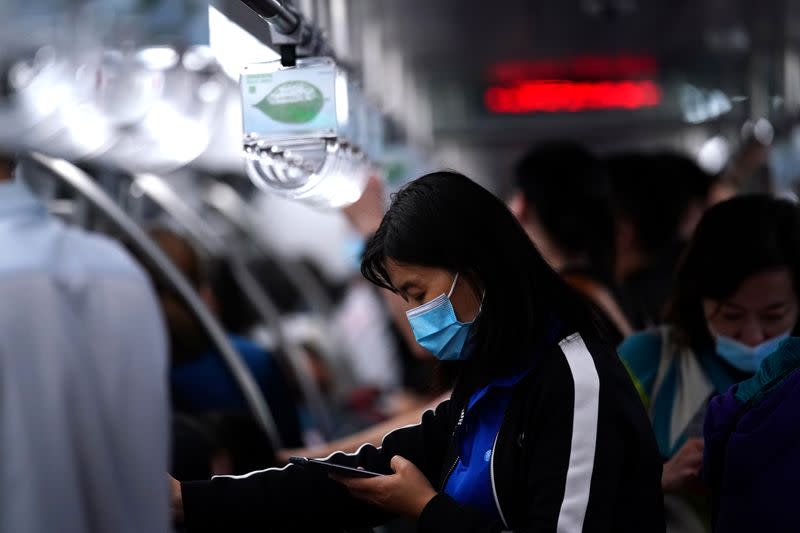 Passenger wearing a face mask uses her phone on a subway train in Beijing