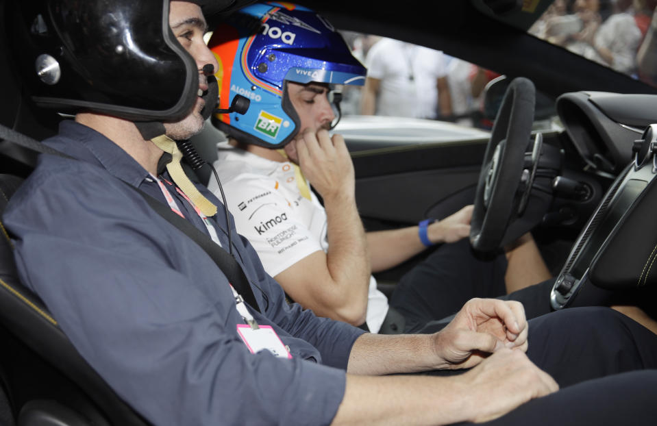 Mclaren driver Fernando Alonso of Spain, right, is flanked by Nascar World champion Jimmie Johnson before driving a McLaren 570S car at the Yas Marina racetrack in Abu Dhabi, United Arab Emirates, Saturday, Nov. 24, 2018. Seven-time NASCAR champion Jimmie Johnson and two-time Formula One champion Fernando Alonso drive Pirelli hot laps together around the Abu Dhabi F1 track on Saturday afternoon. (AP Photo/Luca Bruno)