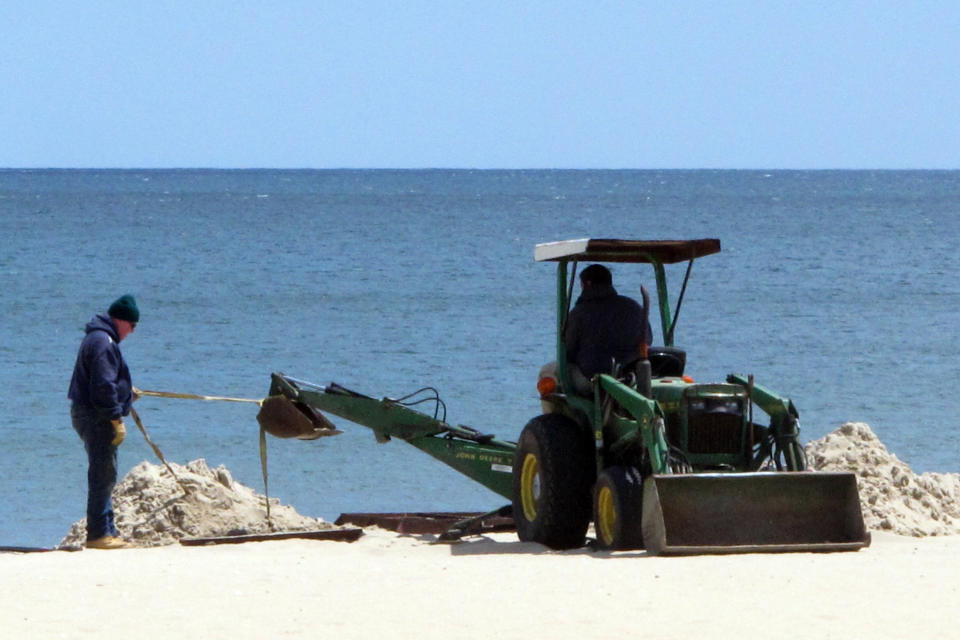 In this Tuesday, May 12, 2020 photo, workers prepare the beach in Belmar, N.J. for the summer season amid the coronavirus pandemic. Gov. Phil Murphy is expected to issue guidelines on Thursday, May 14, 2020, on when and how New Jersey's beaches can begin to reopen during the COVID-19 pandemic. (AP Photo/Wayne Parry)