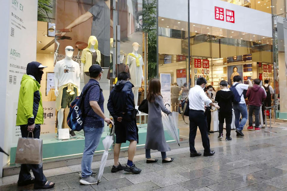 People wait in line at a Uniqlo clothing store at Ginza shopping area in Tokyo, Friday, June 19, 2020. Japanese shoppers queued up in a long line at Uniqlo stores and others clogged up the company’s online shopping site Friday as they rushed to buy washable face masks made from the fashion brand’s fabric for popular underwear line for summertime use.(Kyodo News via AP)