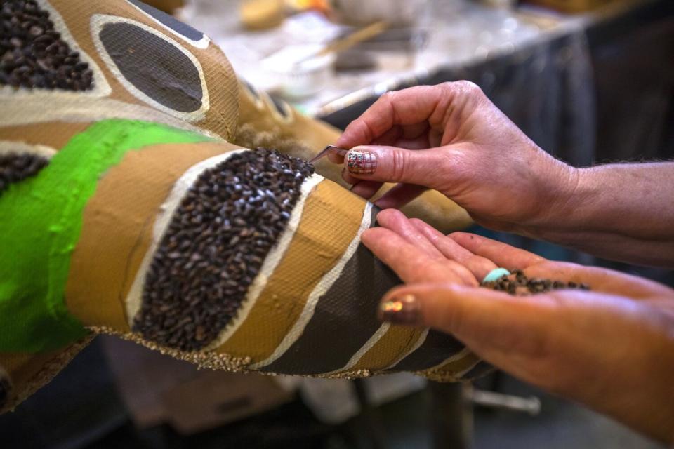 Linda Menard of Tucson uses tweezers while decorating the Louisiana float