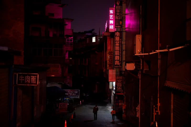 People wear face masks as they walk at a residential community in Xianning of Hubei province