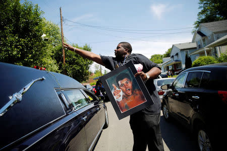 A man throws a rose over the hearse carrying the remains of Muhammad Ali during the funeral procession for the three-time heavyweight boxing champion in Louisville, Kentucky, June 10, 2016. REUTERS/Carlos Barria