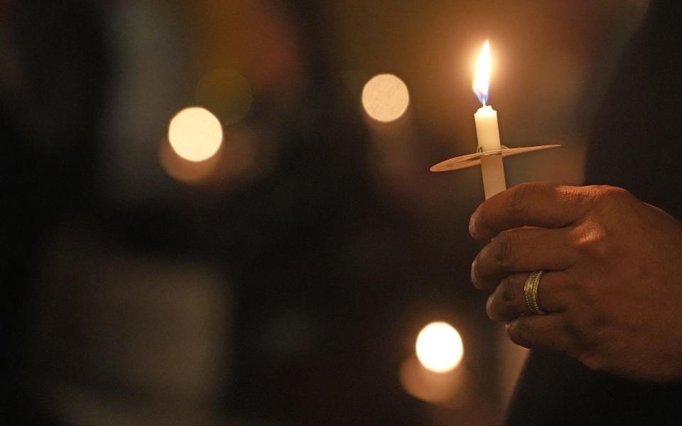 A man holds a candle during the Columbus Coalition For the Homeless 20th Annual Memorial Service for the 94 homeless people who died in Columbus in 2023.