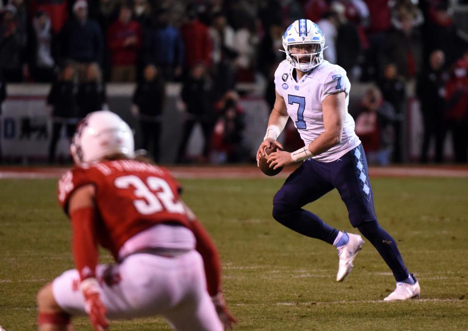 North Carolina quarterback Sam Howell looks to pass on the run with N.C. State linebacker Drake Thomas in coverage Friday night.