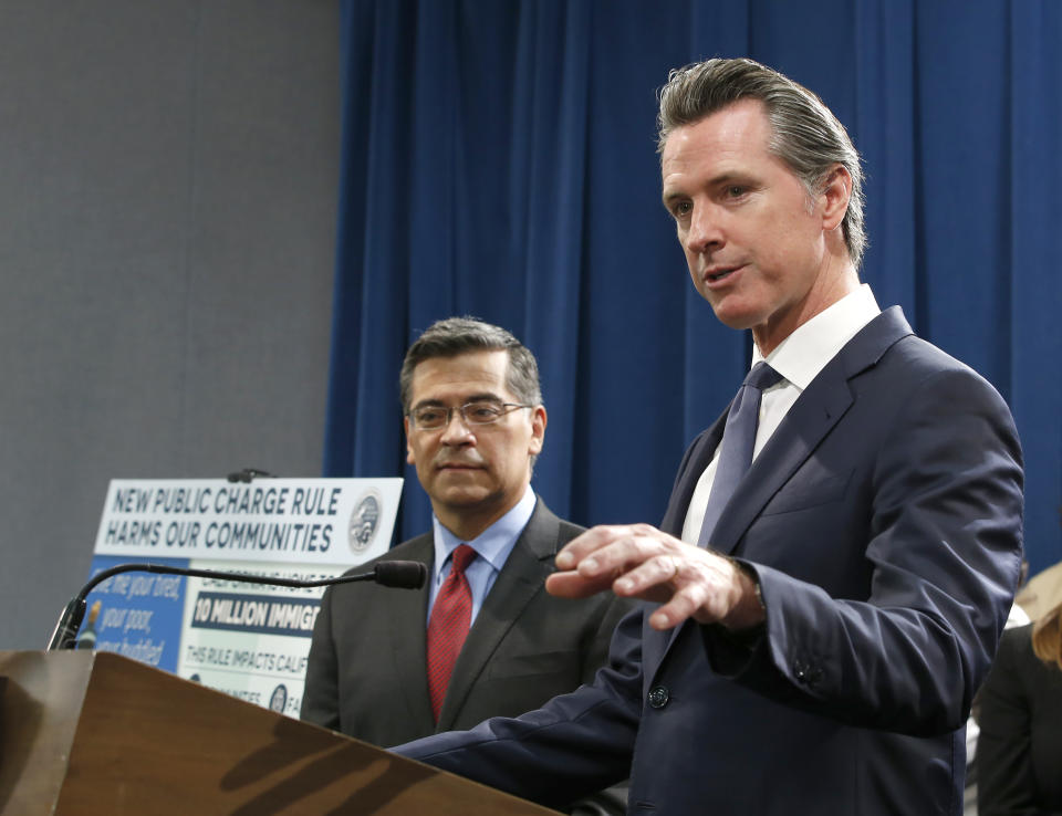 California Gov. Gavin Newsom, right, flanked by Attorney General Xavier Becerra, discusses the lawsuit the state has filed against the Trump administration's new rules blocking green cards for many immigrants who receive government assistance, during a news conference in Sacramento, Calif., Friday, Aug. 16, 2019. California, three other states and the District of Columbia filed the suit Friday against some of the administration's most aggressive moves to restrict legal immigration that are supposed to take effect in October. (AP Photo/Rich Pedroncelli)