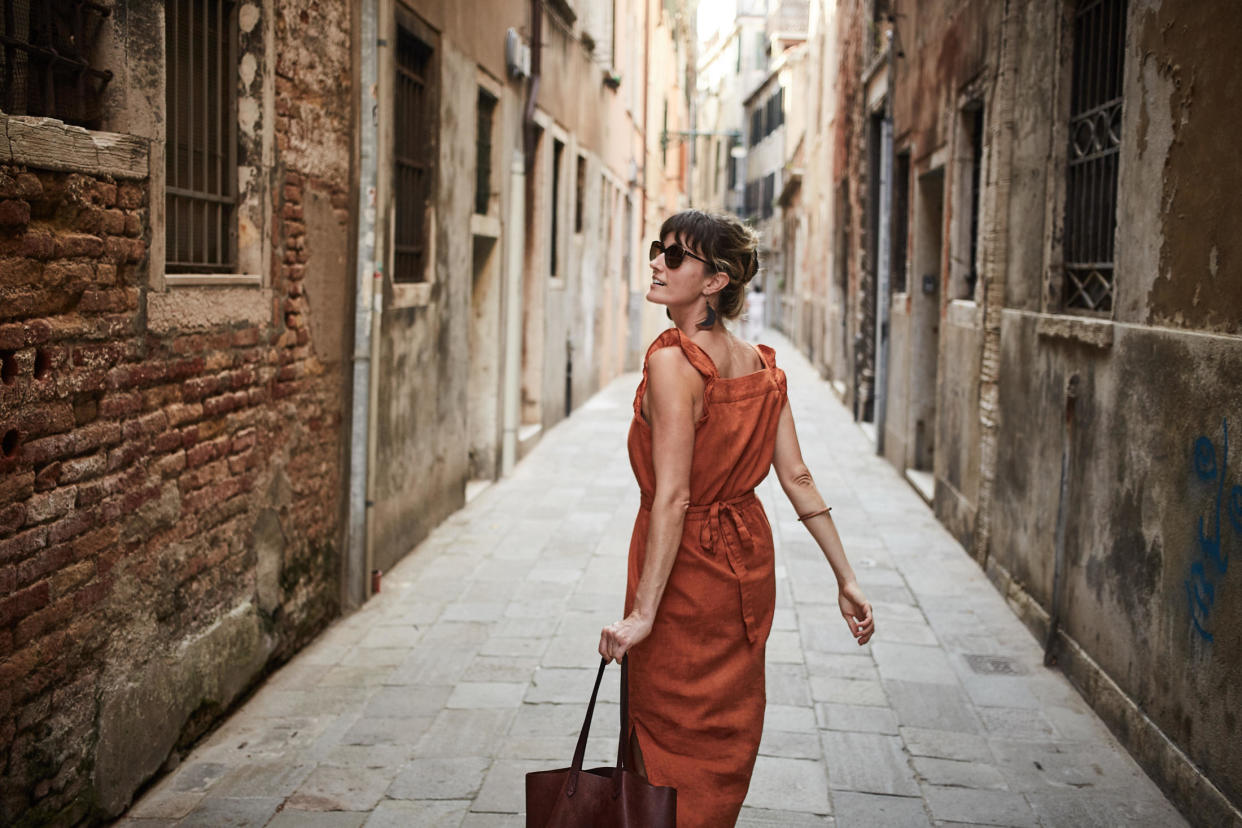 A young woman walks down an old street in Italy / Credit: / Getty Images