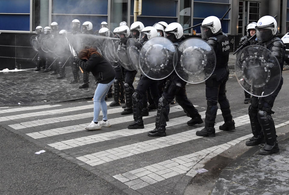 A police officer sprays pepper spray during a protest against coronavirus measures in Brussels, Belgium, Sunday, Dec. 5, 2021. Hundreds of people marched through central Brussels on Sunday to protest tightened COVID-19 restrictions imposed by the Belgian government to counter the latest spike in coronavirus cases. (AP Photo/Geert Vanden Wijngaert)