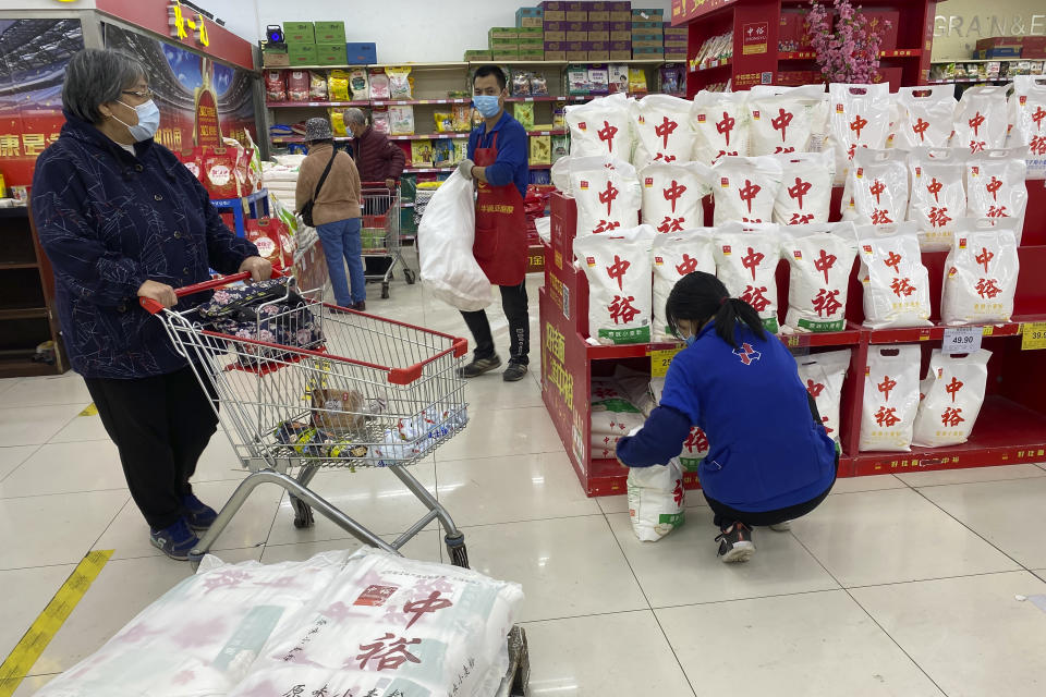 Store clerks re-stock bags of flour at a supermarket in Beijing, China, Wednesday, Nov. 3, 2021. A recent seemingly innocuous government recommendation for Chinese people to store necessities for an emergency quickly sparked scattered instances of panic-buying and online speculation of imminent war with Taiwan. (AP Photo/Ng Han Guan)