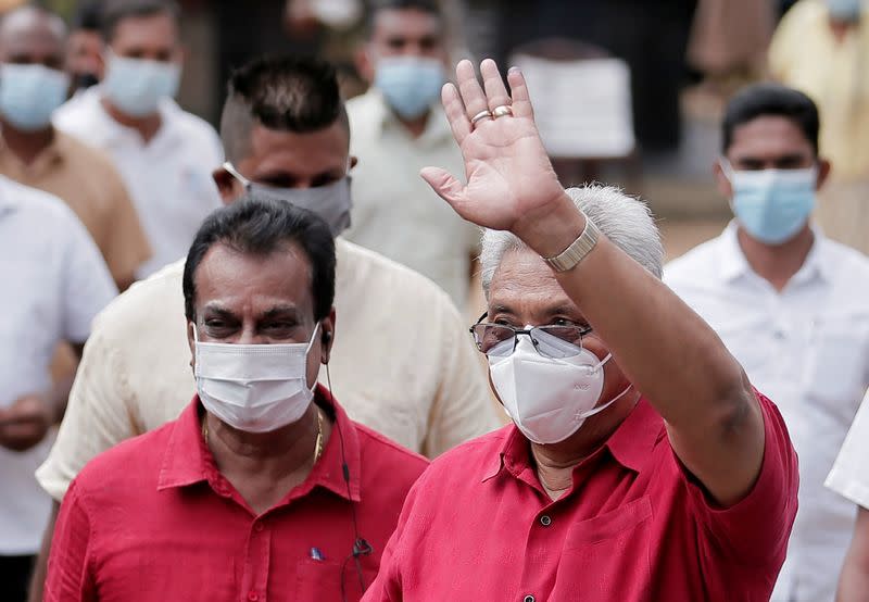 Sri Lanka's President Rajapaksa wears a protective mask as he waves to supporters while leaving a polling station in Colombo