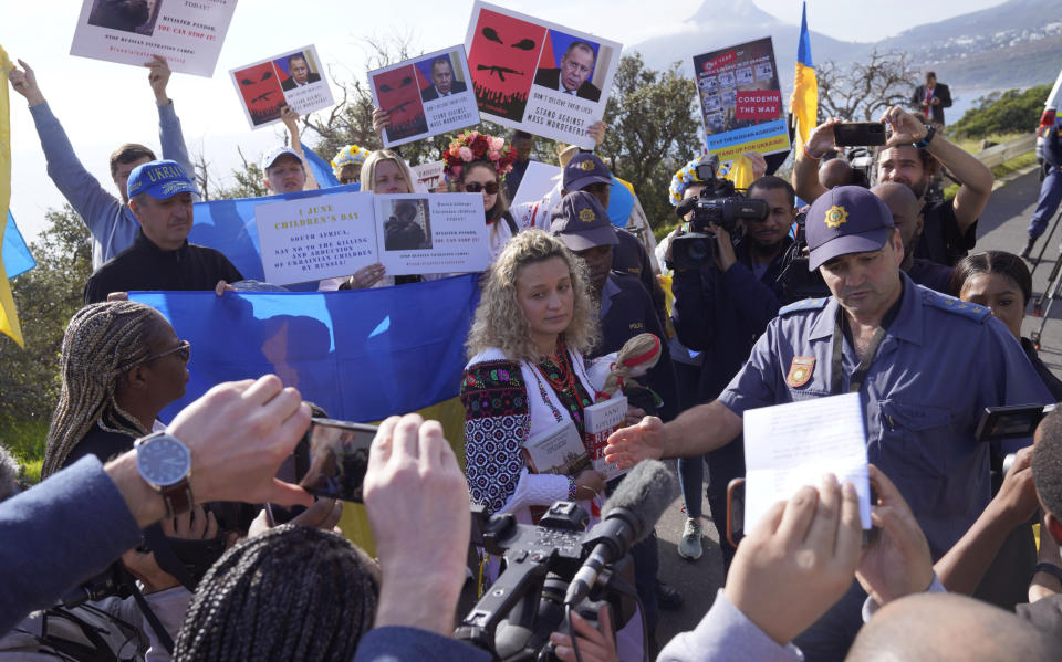 A policeman wards off Ukrainian demonstrators who protested at a venue where the Russian and Chinese foreign ministers are set to meet with their counterparts from the BRICS economic bloc of developing nations in Cape Town, South Africa Thursday, June 1, 2023. The meeting is a precursor to a larger summit of developing nations in South Africa in August that Russian President Vladimir Putin may attend while under indictment by the International Criminal Court. (AP Photo/Nardus Engelbrecht)