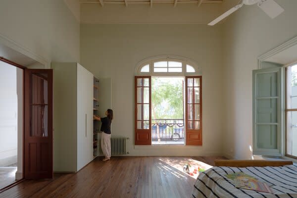 Florian’s bedroom sits across from the showroom for Micaela’s lifestyle brand, Agave. The burnt-red trim of the door that connects the hall to the bedroom matches the other wood-and-glass doors and windows, as well as the custom kitchen cabinets.