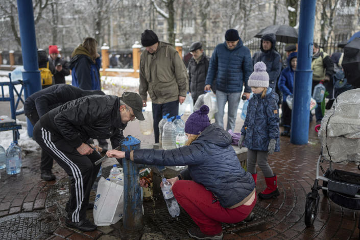 People collect water, in Kyiv, Ukraine, Thursday, Nov. 24, 2022. Residents of Ukraine's bombed but undaunted capital clutched empty bottles in search of water and crowded into cafés for power and warmth Thursday, switching defiantly into survival mode after new Russian missile strikes a day earlier plunged the city and much of the country into the dark. (AP Photo/Evgeniy Maloletka)