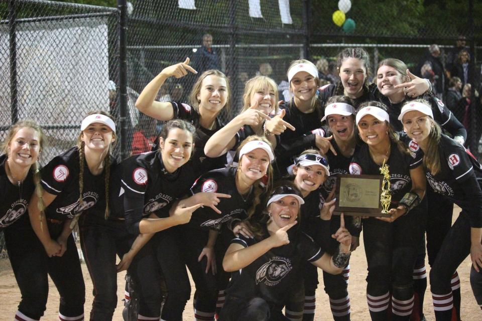 New Boston Huron's softball team poses with the trophy after clinching the Huron League championship Thursday with a 13-4 win over Flat Rock