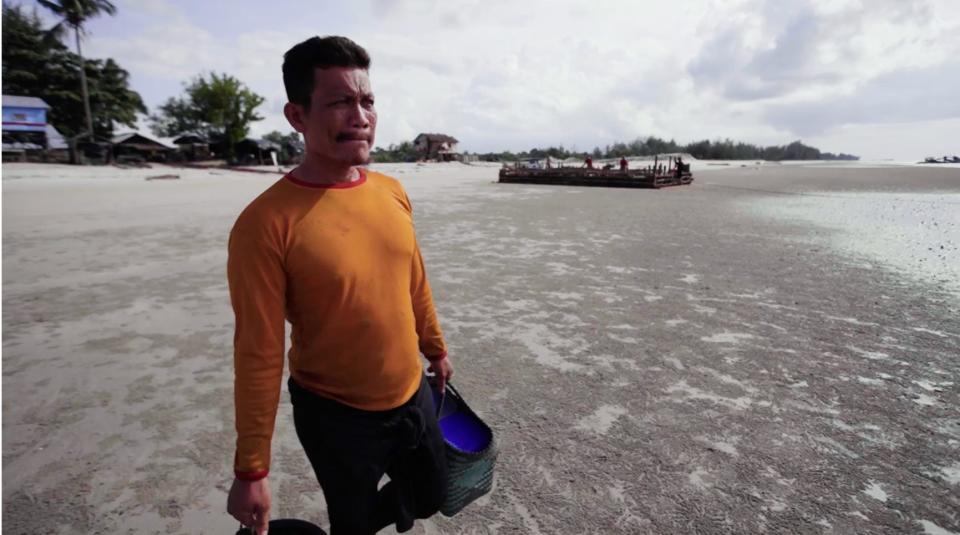 Joko Tngkir walks from the beach to his mining pontoon to start his workday