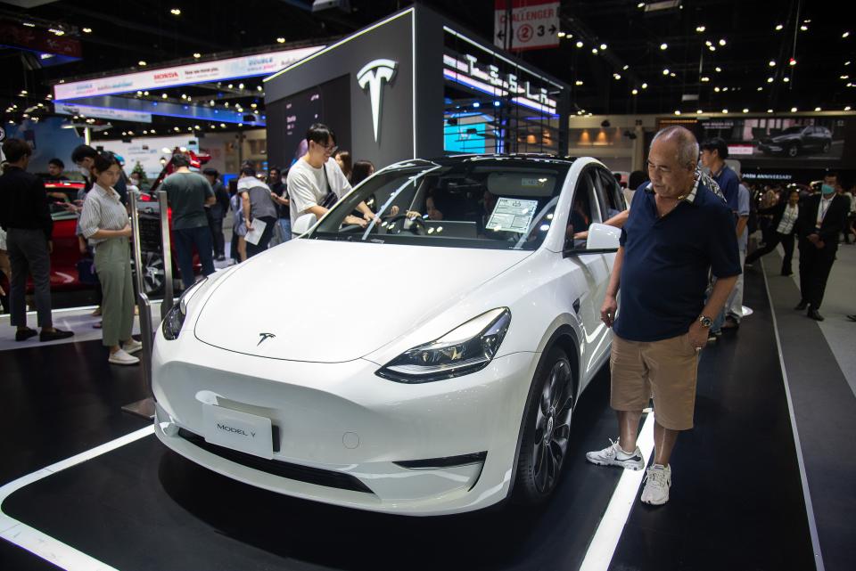 People inspect a Tesla Model Y car.