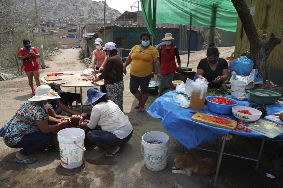 Residentes cocinan con vegetales donados en el barrio de chabolas de Villa María en Lima, Perú, el martes 2 de febrero de 2021, en medio de un segundo cierre completo de actividades mientras el país lucha contra un resurgimiento en los casos de COVID-19. La falta de ingresos estables ha obligado a muchas familias a depender de los comedores comunitarios en algunos de los barrios más pobres de la capital. (AP Foto/Martin Mejia)