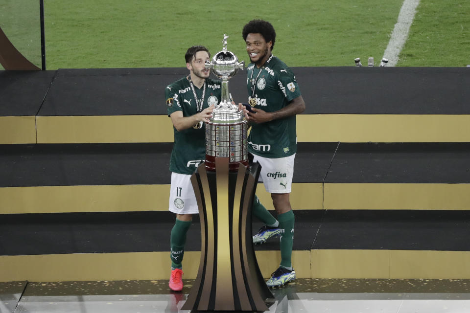 Rony of Brazil's Palmeiras, left, and teammates Luiz Adriano look at the trophy after beating 1-0 Brazil's Santos in the Copa Libertadores final soccer match at the Maracana stadium in Rio de Janerio, Brazil, Saturday, Jan. 30, 2021. (AP Photo/Silvia Izquierdo)