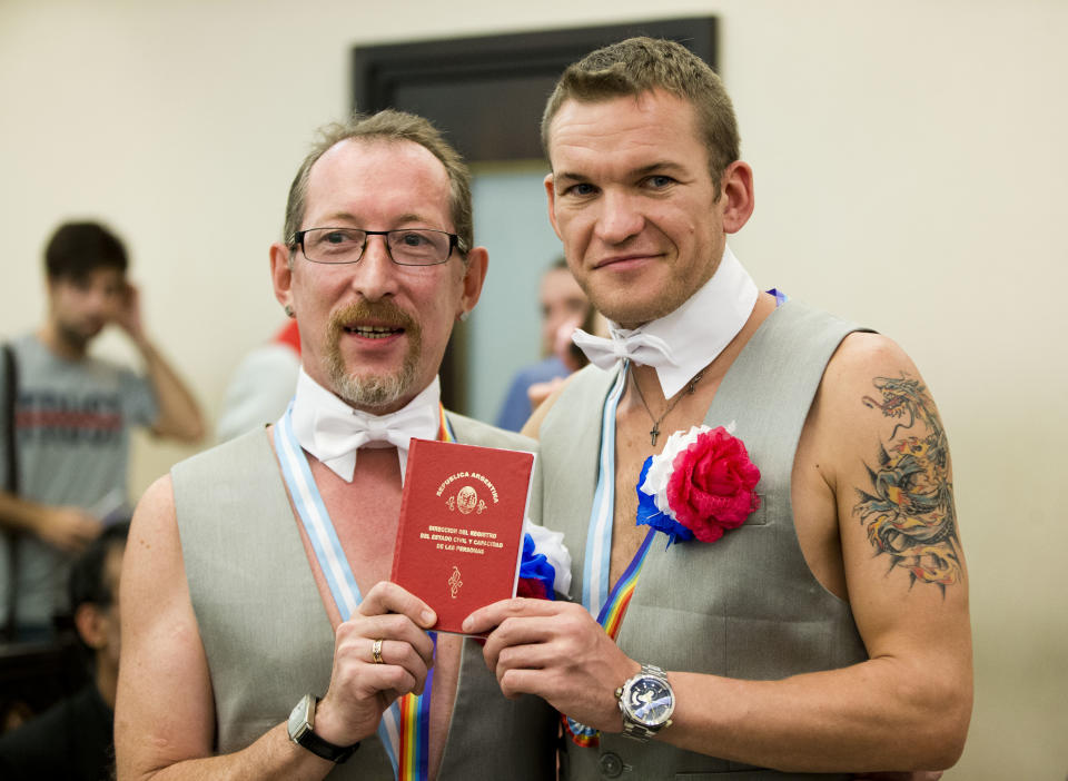 Russian newlyweds Alexander Emereev, left, and Dmitry Zaytsev pose with their marriage book in Buenos Aires, Argentina, Tuesday, Feb. 25, 2014. The two men, who are from Sochi, planned to apply for political asylum after their marriage ceremony at the civil registry in Buenos Aires. (AP Photo/Victor R. Caivano)