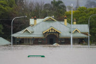 A building is inundated with water on the far side of the Windsor Bridge at Windsor on the outskirts of Sydney, Australia, Tuesday, July 5, 2022. Hundreds of homes have been inundated in and around Australia’s largest city in a flood emergency that was impacting 50,000 people, officials said Tuesday.(AP Photo/Mark Baker)