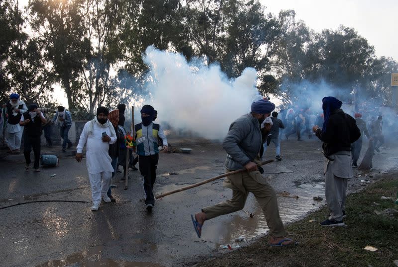 Farmers run for cover amidst tear gas smoke fired by police, at Shambhu