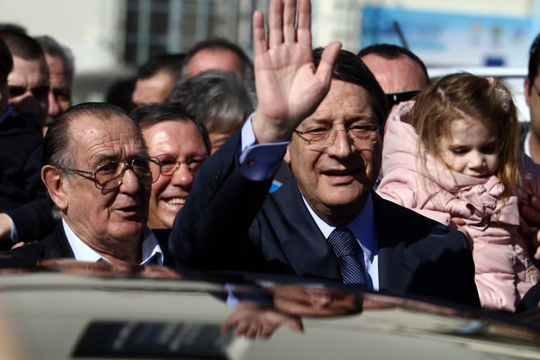 Presidential candidate for the Democratic Rally of Cyprus (DISY) party, Nicos Anastasiades waves as he leaves a polling station after voting for the first round of Cyprus' presidential election on February 17, 2013 in Limassol