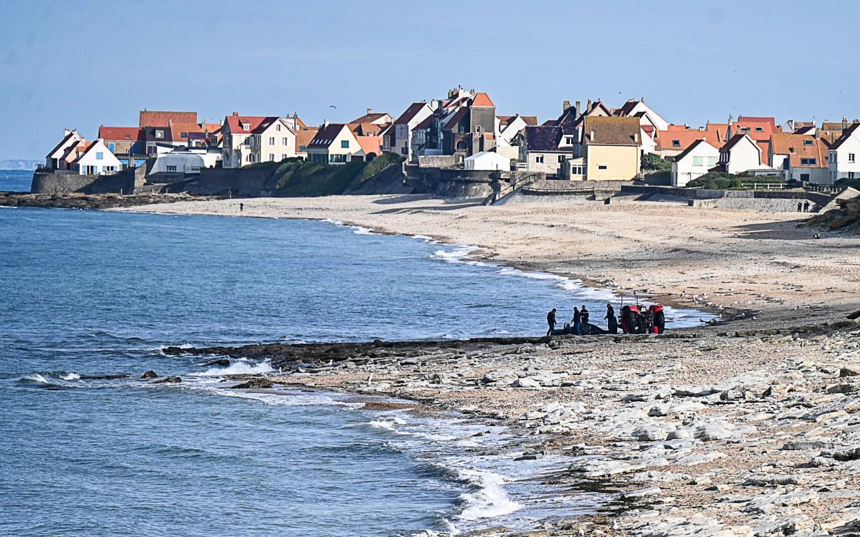 French gendarme use a tractor to pull a damaged migrant boat near the beach of Ambleteuse in northern France