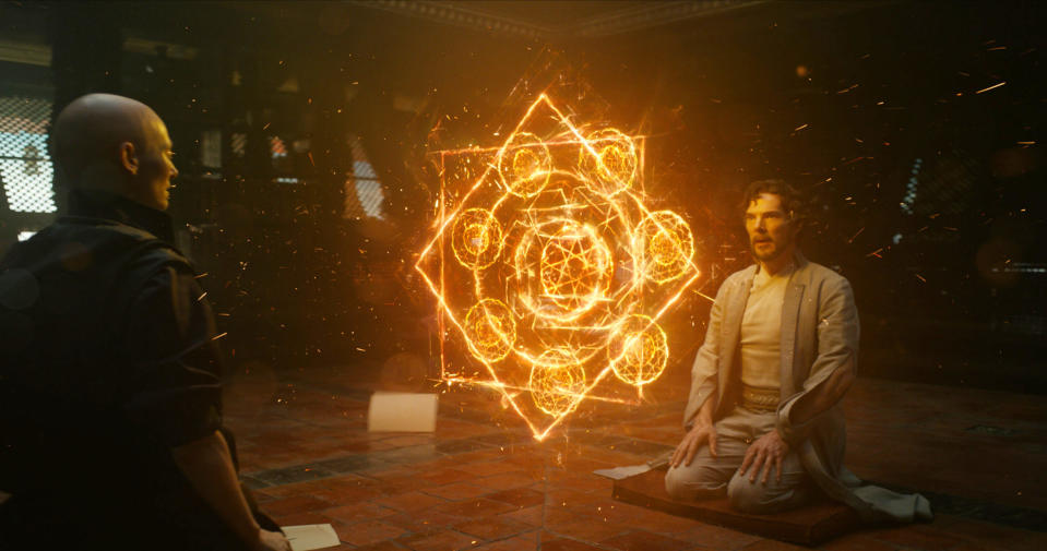 Doctor Strange sits on the floor with another man and looks at a portal