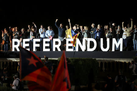 People wave from the stage behind the word "Referendum" during a closing rally in favour of the banned October 1 independence referendum in Barcelona, Spain, September 29, 2017. REUTERS/Susana Vera