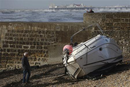 A man walks alongside a yacht washed up on the beach after storms battered Brighton in south east England October 28, 2013. REUTERS/Luke MacGregor