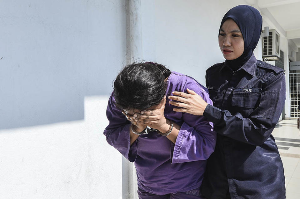 The Nigerian female suspect covers her face as she is led to the Magistrate Court in Sepang May 27, 2019.