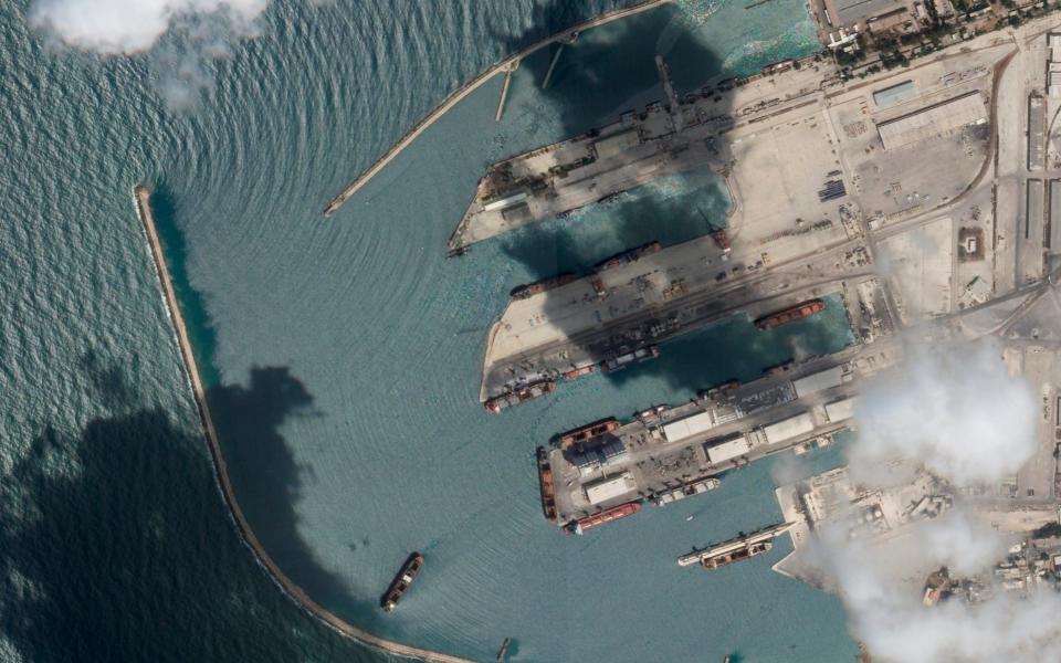 Satellite image of the Sierra Leone-flagged cargo ship Razoni, centre bottom, at port in Tartus, Syria with four white cranes on its red deck on Monday - Planet Labs PBC