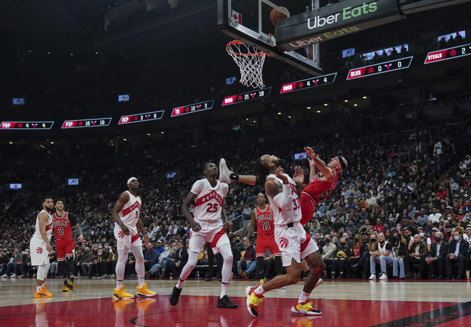 Chicago Bulls guard Alex Caruso (6) is fouled by Toronto Raptors guard Gary Trent Jr. (33) as Raptors forward Chris Boucher (25) looks on during first-half NBA basketball game action in Toronto, Monday, Oct. 25, 2021. (Nathan Denette/The Canadian Press via AP)