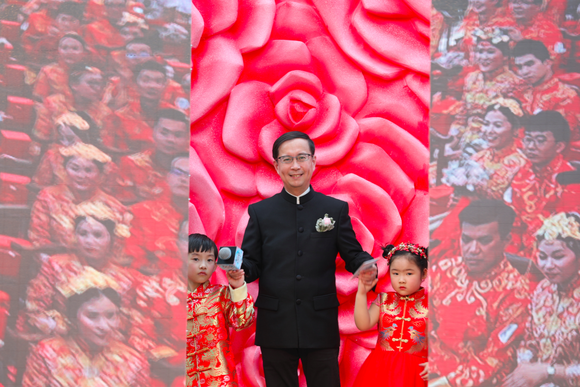 Alibaba CEO Daniel Zhang stands with a little girl and a little boy who are both wearing decorative red outfits during Ali-Day