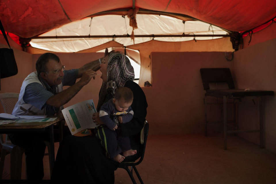 In this Saturday, June 16, 2012 photo, a general physician examines a Palestinian woman in the West Bank town of Susiya. Palestinian herders in this hamlet have clung to arid acres spread over several West Bank hills for decades, even as Israel forced them to live off the grid while providing water and electricity to nearby Jewish settlements and unauthorized outposts. But the end seems near for Susiya's 200 residents: Citing zoning violations, Israel is threatening to demolish the village, including German-funded solar panels. (AP Photo/Bernat Armangue)