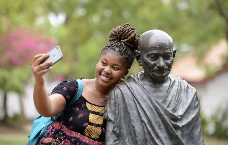 <p>An African-American visitor poses for a selfie photograph with the statue of Indian independence icon Mahatma Gandhi at the Mahatma Gandhi Ashram in Ahmedabad on June 19, 2016. </p>