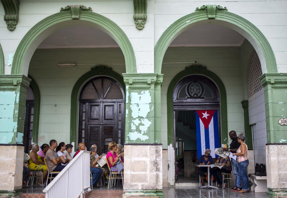 En esta imagen, tomada el 30 de septiembre de 2018, un grupo de vecinos participa en un foro público sobre una reforma constitucional en La Habana, Cuba. Tras escuchar el himno nacional en pie, los participantes comparten sus opiniones mientras un secretario toma notas que serán enviadas de alguna forma a la comisión para la reforma constitucional, presidida por Raúl Castro. (AP Foto/Desmond Boylan)