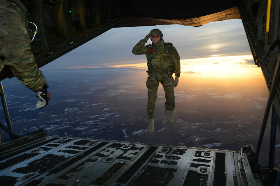 A U.S. Soldier assigned to 1st Battalion, 10th Special Forces Group (Airborne) salutes his fellow Soldiers while jumping out of a C-130 Hercules aircraft over a drop zone in Germany, Feb. 24, 2015. 