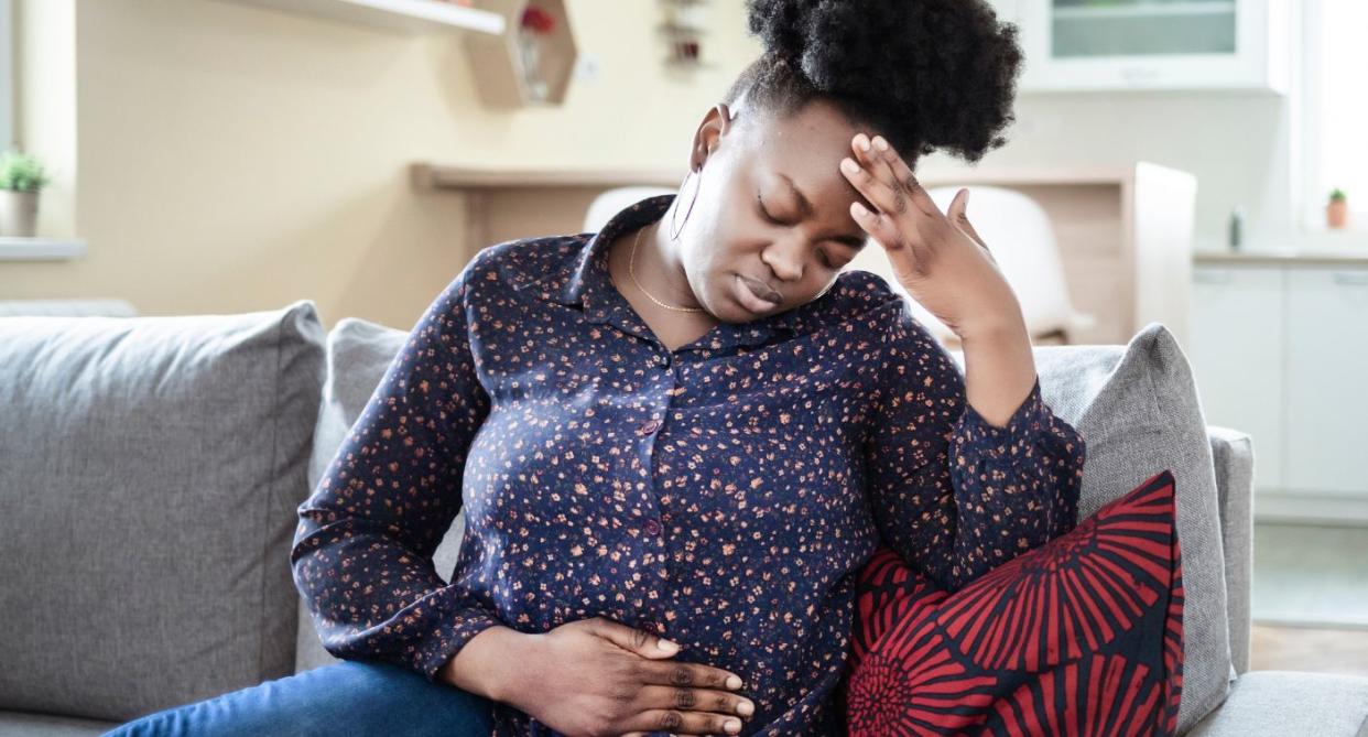 Woman holding stomach in pain due to hormones. (Getty Images)