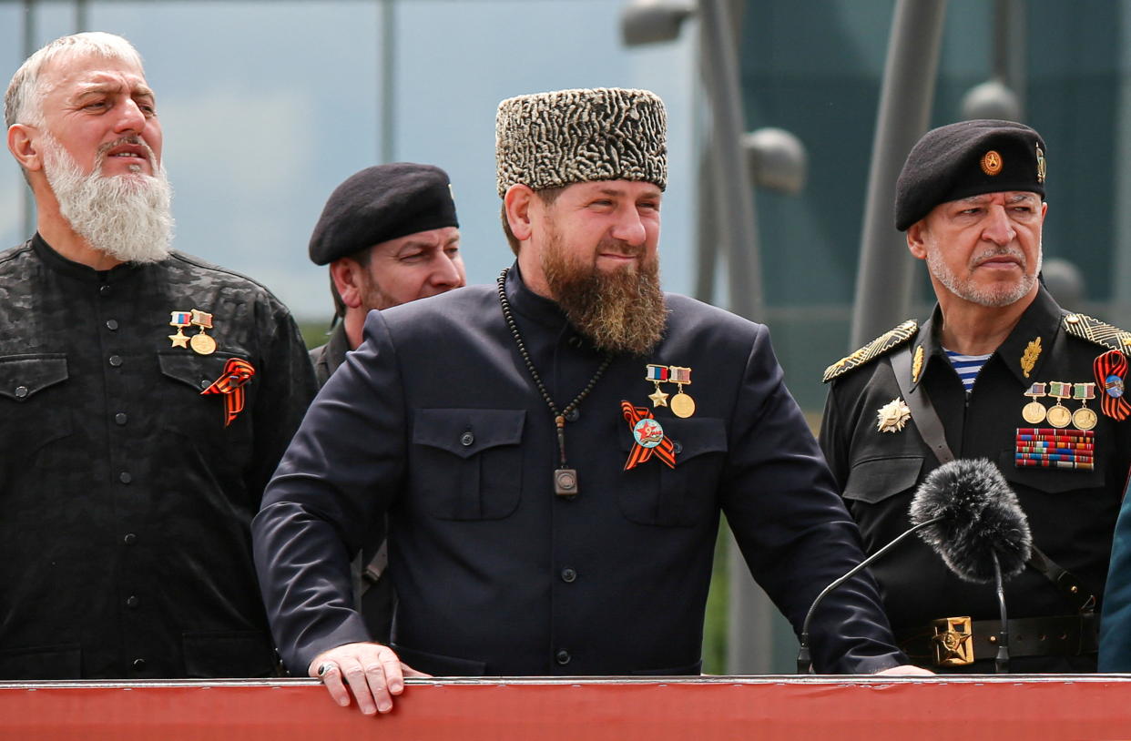 Head of the Chechen Republic Ramzan Kadyrov and other Chechen leaders stand together behind a barrier.