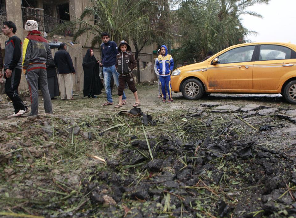 Iraqi civilians inspect the site of a car bomb in a commercial area in the northern Hurriyah neighborhood of Baghdad, Iraq, Monday, Feb. 3, 2014. Iraqi officials say car bombings on Monday in and near Baghdad have killed and wounded scores of people. (AP Photo/Hadi Mizban)