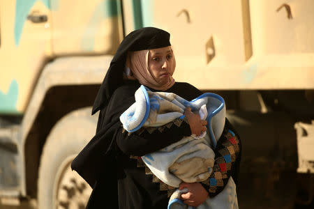 A displaced Iraqi woman, who fled her home during a battle between Iraqi forces and Islamic State militants, carries her baby in Mosul, Iraq March 9, 2017. REUTERS/Thaier Al-Sudani