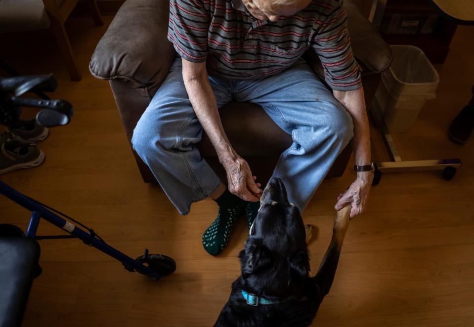 Meadow Brook Medical Care Facility resident Butch Craig, 80, gives a bone to Scout after shaking his paw on Thursday, July 13, 2023.